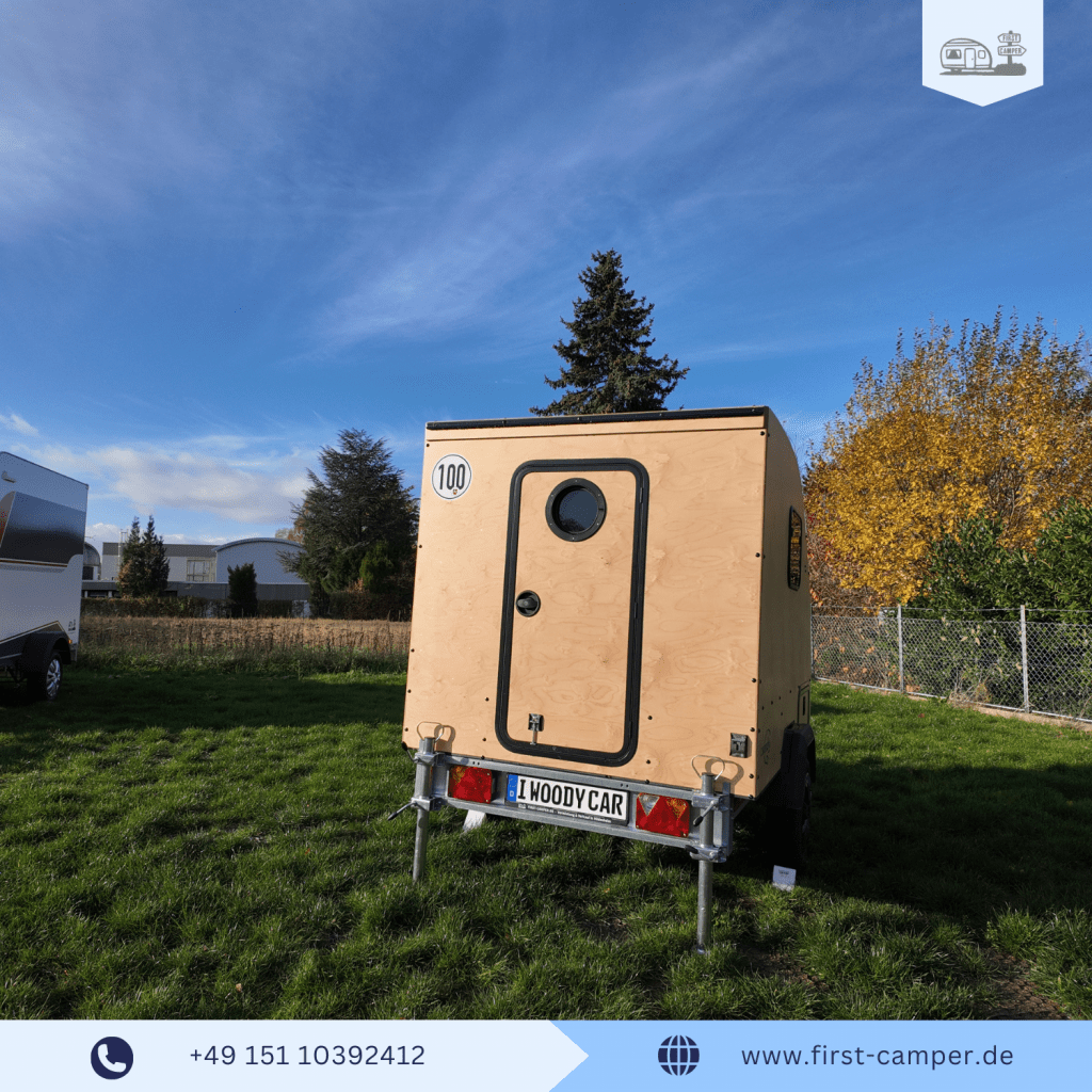 Heckansicht des i:woody car – handgefertigter Mini Holzwohnwagen aus Manufaktur mit natürlicher Holzrückseite und geöffneter Hecktür