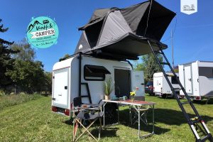 Kompakter Camping-Trailer mit aufgeklapptem Dachzelt auf der Vanlife & Camper Messe in Springe.